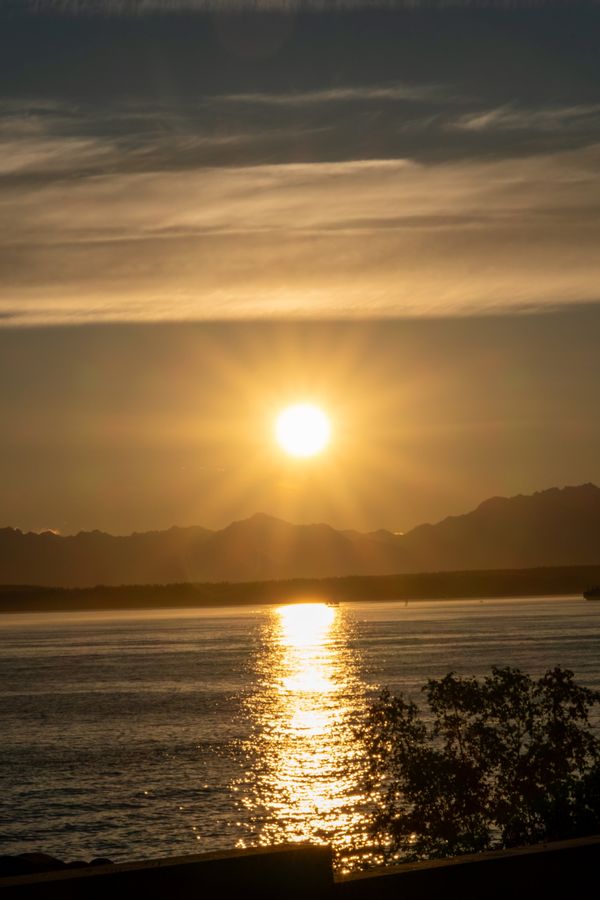 The sun sets over the Olympic Mountains with a gold reflection across Puget Sound